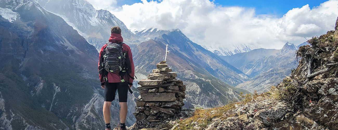 Mand på vandretur kigger ud på udsigten i bjergene
