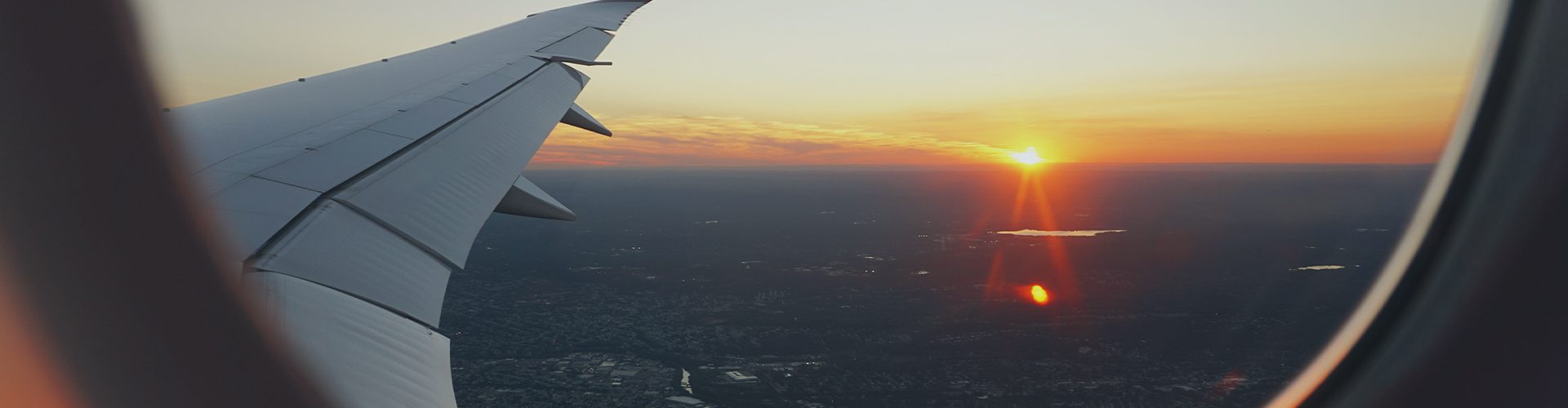 Udsigt fra et flyvindue mod solnedgang