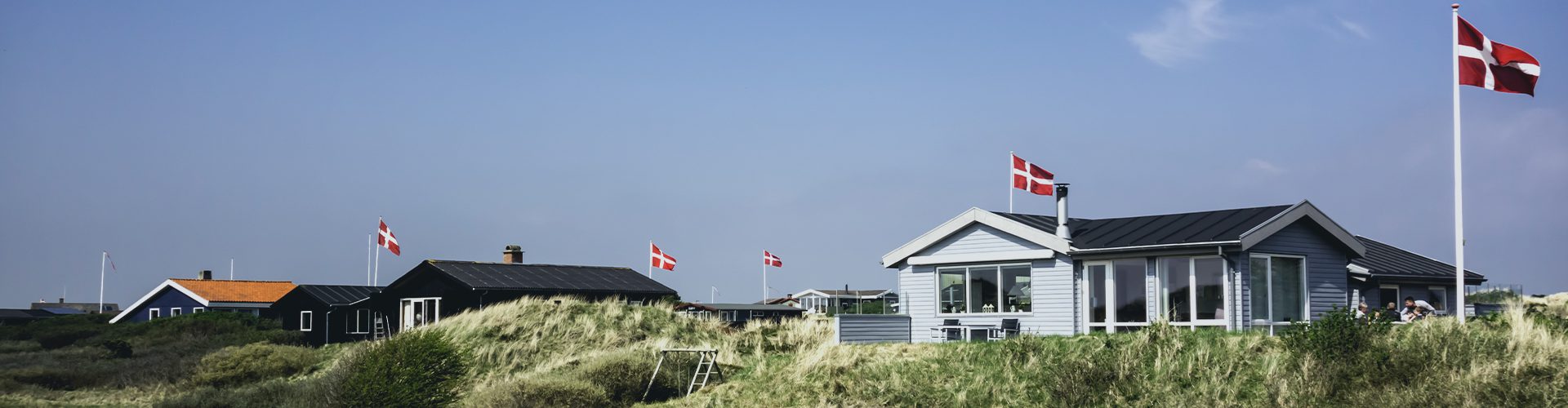 Sommerhuse i klitlandskab med danske flag