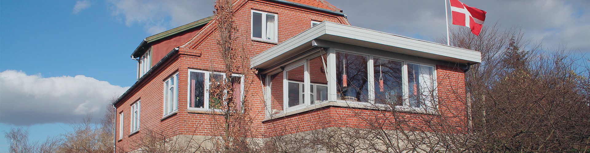 Murstensvilla på en forårsdag med dansk flag