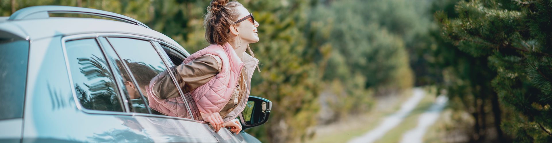 Kvinde hænger ud af bilrude i skoven