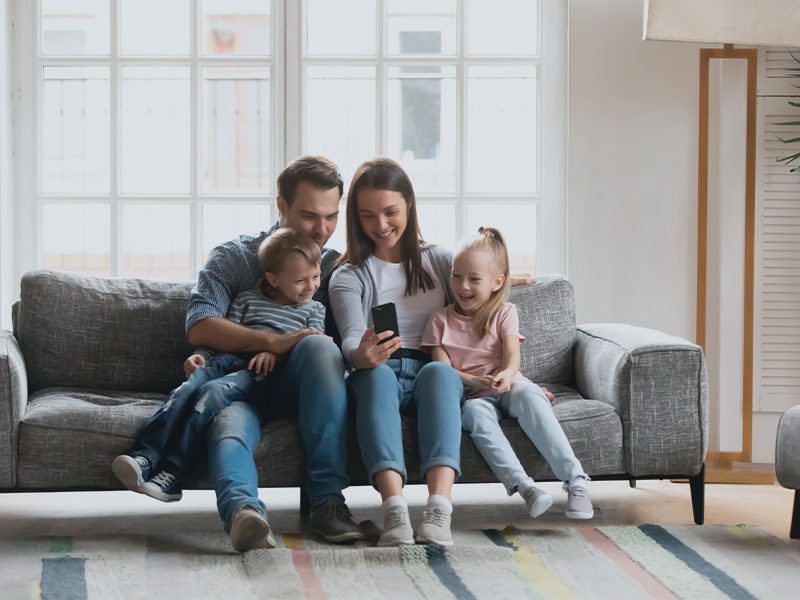 Familie i sofa ser på telefon