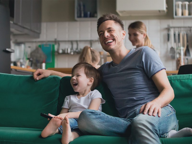 Far og søn griner i sofa