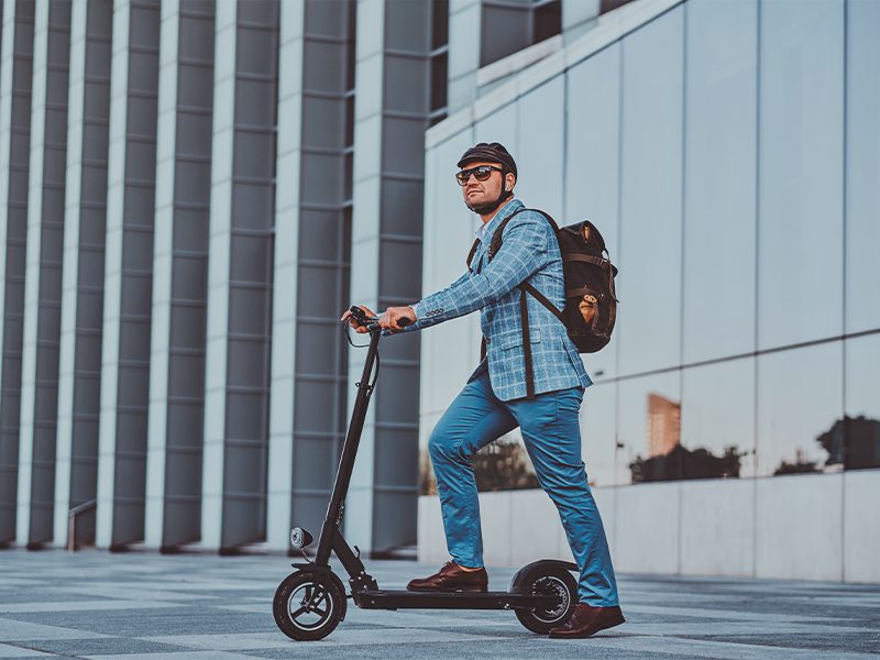 Mand på el-løbehjul med cykelhjelm