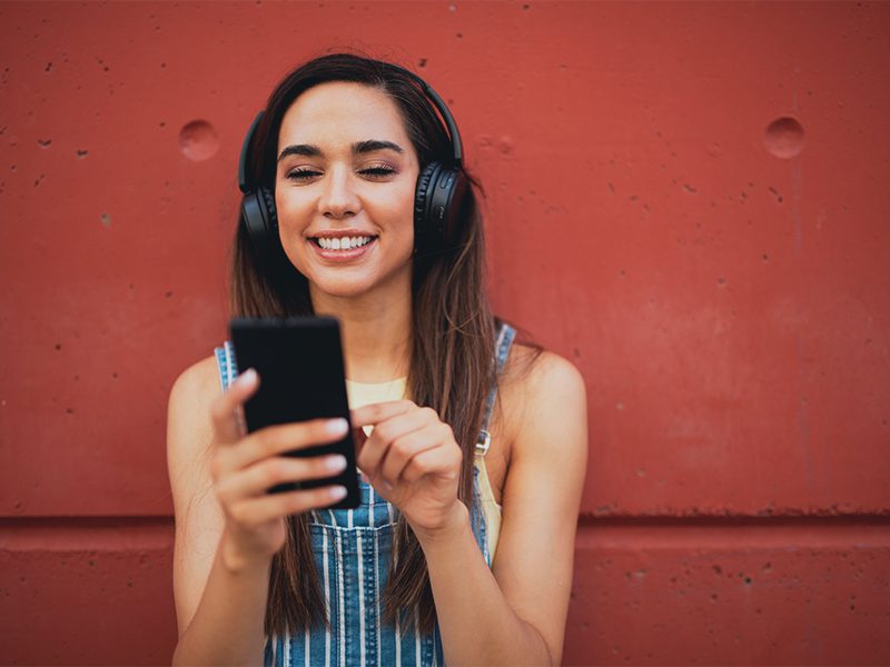 Ung pige med hørebøffer og telefon