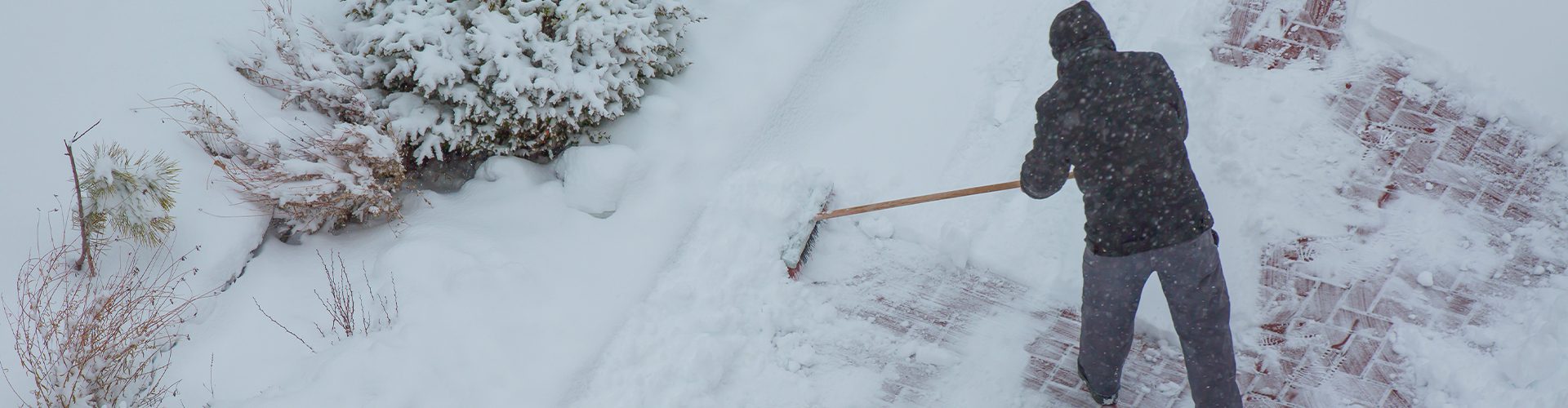 Mand rydder sne på fliser
