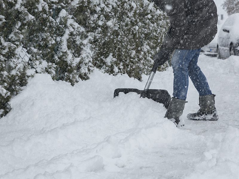 Kvinde rydder sne med sneskovl