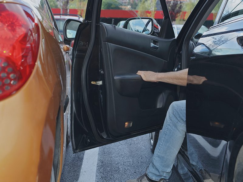 Bildør ved parkeret bil åbnes af mand