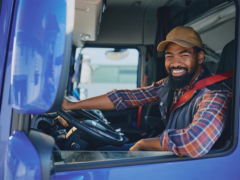 Farvet mand som lastbilchauffør i blå lastbil