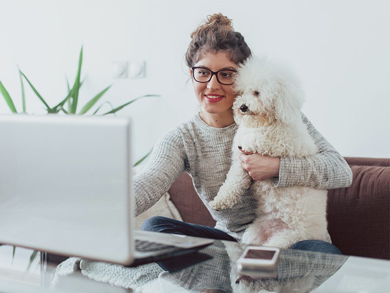 Kvinde og hund sidder sammen ved computer